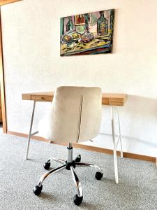 einen Schreibtisch mit einem Stuhl vor einem Gemälde in der Unterkunft Wunderschöne Maisonette-Ferienwohnung in stattlichem Toggenburgerhaus in Sankt Peterzell