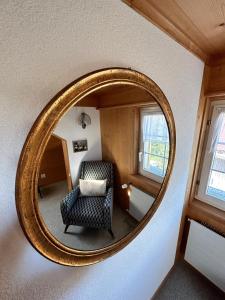 espejo ovalado en una habitación con silla en Wunderschöne Maisonette-Ferienwohnung in stattlichem Toggenburgerhaus en Sankt Peterzell