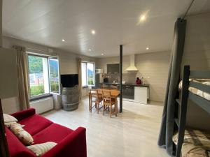 a living room with a red couch and a kitchen at Cauterets Charmant Studio 4 personnes in Cauterets