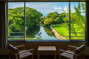 ein Fenster mit Blick auf einen Fluss durch ihn hindurch in der Unterkunft KAMENOI HOTEL Yanagawa in Yanagawa