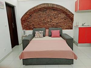 a bedroom with a bed and a brick wall at Estúdio no centro histórico in Évora