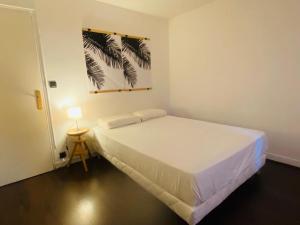 a bedroom with a large white bed and a lamp at La cinéroom in Bon-Encontre