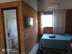 a small bedroom with a bed and a brick wall at Casa Studio Uirá em Chapada dos Guimarães in Chapada dos Guimarães