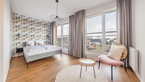 ein Schlafzimmer mit einem Bett und einem Stuhl und Fenstern in der Unterkunft Residence I Jastrzębia Góra, Sun & Snow in Jastrzębia Góra