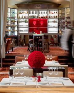 un restaurante con mesas con copas de vino y flores rojas en Hôtel Le Royal Monceau Raffles Paris en París