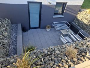 a house with a patio with a bench and rocks at FeWo Mösle in Lautrach