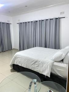 a bedroom with a bed and a glass table at Amethyst bed and breakfast in Lilongwe