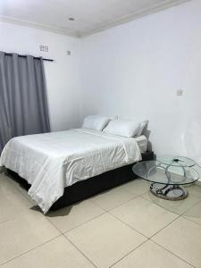 a white bedroom with a bed and a glass table at Amethyst bed and breakfast in Lilongwe