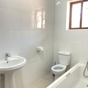 a white bathroom with a toilet and a sink at Amethyst bed and breakfast in Lilongwe