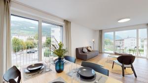 ein Esszimmer mit einem Tisch und Stühlen sowie einem großen Fenster in der Unterkunft Bright & modern apartments in Sion in Sion