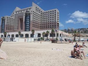 a group of people sitting on the beach in front of a building at beach Apartments in Haifa
