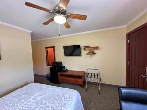 a bedroom with a ceiling fan and a bed and a desk at Travellers Inn Fredericton NB in Waasis