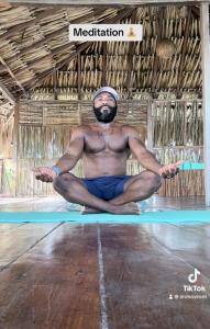 a man sitting in a yoga pose on a mat at Eco Hostal Villa Canada - A Sustainable Oasis on Isla de Tierra Bomba in Playa Punta Arena