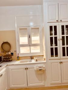 a kitchen with white cabinets and a sink at Appartement Vue de Mer Pied dans l'eau in Gabès