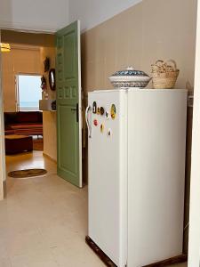 a white refrigerator in a kitchen with a green door at Appartement Vue de Mer Pied dans l'eau in Gabès