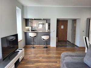 a living room with two bar stools and a kitchen at Apartament Bryza Aquarius - z miejscem parkingowym in Ustka