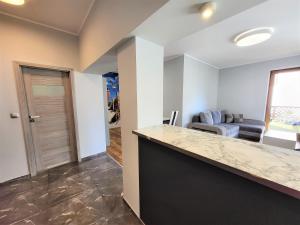 a kitchen with a counter top and a living room at Apartament Bryza Aquarius - z miejscem parkingowym in Ustka