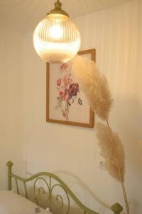 a lamp with a feather on a wall next to a bed at Traveler’s home in Visoko