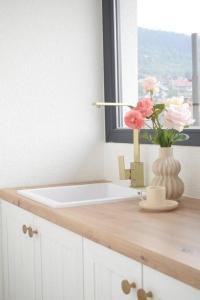 a bathroom counter with a vase of flowers and a window at Traveler’s home in Visoko