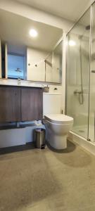 a bathroom with a toilet and a glass shower at Apartamento Greta Río CalleCalle in Valdivia