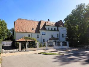 een groot wit huis met een hek ervoor bij Rittergut Dornreichenbach 