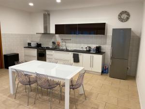 uma cozinha com uma mesa branca com cadeiras e um frigorífico em B&B Mandorli 29 em San Colombano al Lambro