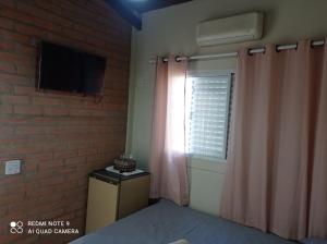 - une chambre avec une fenêtre et une télévision sur un mur en briques dans l'établissement Casa Stúdio Uirá - suíte, à Chapada dos Guimarães