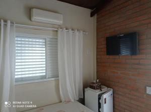 a bedroom with a window and a white refrigerator at Casa Stúdio Uirá - suíte in Chapada dos Guimarães