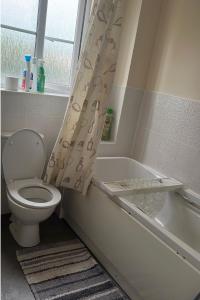 baño con aseo, bañera y ventana en Salimi, en Bridgend