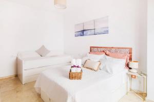 una camera bianca con due letti e un cesto sul letto di Compas Suites a Málaga
