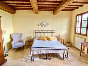 a bedroom with a bed and a chair at Relais Poggio Del Melograno in Montecatini Val di Cecina