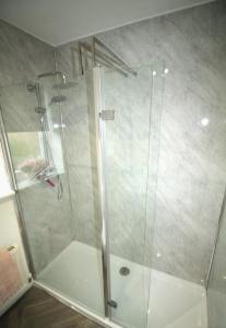 La salle de bains est pourvue d'une douche avec une porte en verre. dans l'établissement Ashington - 2 Bedroom House - Beautifully Decorated & Furnished - Large Garden, à Ashington