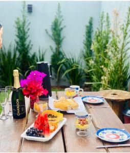 a wooden table with food and a bottle of champagne at Bangalô Miraflores in Chapada dos Guimarães