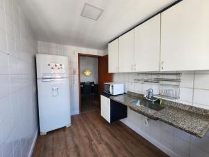 a kitchen with a white refrigerator and a sink at Apartamento Enseada do Suá in Vitória