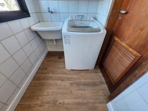 un piccolo bagno con lavatrice e lavandino di Apartamento Enseada do Suá a Vitória