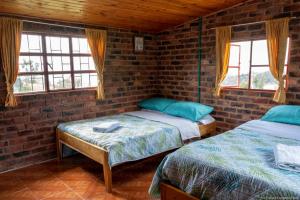 two beds in a room with two windows at Cabaña Campestre La Esperanza in Duitama