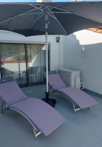 duas cadeiras roxas debaixo de um guarda-sol num quarto em Apartamento de Bem Estar em São Pedro do Sul
