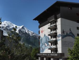 um edifício com uma montanha coberta de neve ao fundo em Chalet Hôtel Le Prieuré & Spa em Chamonix-Mont-Blanc