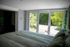 una camera da letto con un letto e una grande finestra di L'écurie gîte chambre a Spa