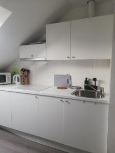 a white kitchen with white cabinets and a sink at Apartments Simple Teslina in Zagreb