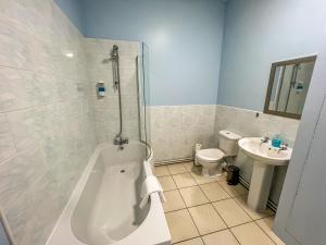 a bathroom with a tub and a toilet and a sink at County Hall Apartment Hotel in Boston