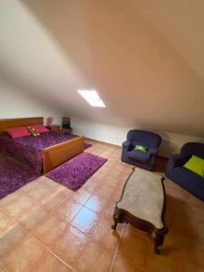 a attic bedroom with two beds and two chairs at Casa da Leonor in Viseu