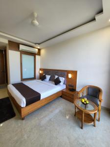 een slaapkamer met een bed, een tafel en een stoel bij Sukoon Signature in Indore