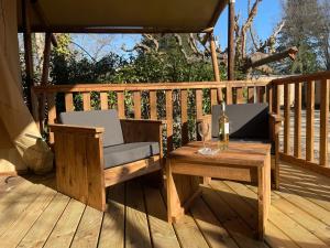 eine Holzterrasse mit einem Tisch und einem Glas Wein in der Unterkunft Lodges & Nature - 49 in Avignon