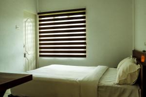 a bedroom with a white bed and a window at ADONAY INN RESIDENCY in Kalpetta
