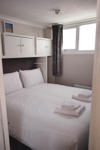 a bedroom with a large white bed with towels on it at Immaculately Presented Detached Family Chalet - 5 mins to beach, nr Great Yarmouth & Norfolk Broads in Great Yarmouth