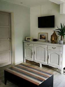 um quarto com um armário branco com uma televisão na parede em Le Petit Paradis de Noordpeene em Noordpeene