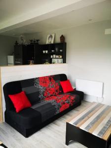 um sofá preto numa sala de estar com almofadas vermelhas em Le Petit Paradis de Noordpeene em Noordpeene