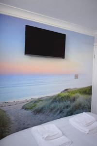 a flat screen tv hanging on a wall with a beach at Immaculately Presented Detached Family Chalet - 5 mins to beach, nr Great Yarmouth & Norfolk Broads in Great Yarmouth