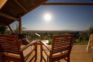 una mesa y sillas en una terraza con el sol en el cielo en Glamping Grancia, en Grosseto